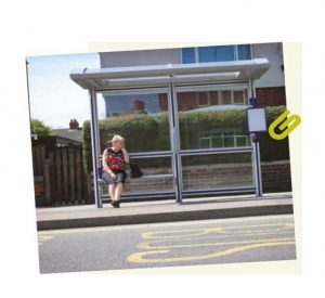 Lady sat a undercover glass bus stop and shelter